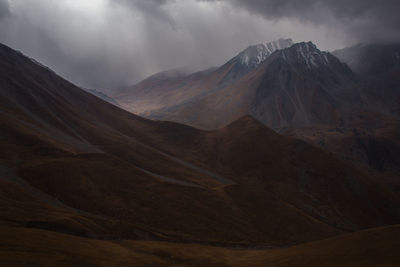 Mountain gorge with mountain peaks in autumn in bad weather, rain and clouds