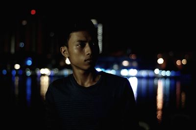 Portrait of young man looking away in city at night