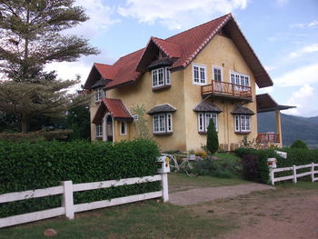 House amidst trees and buildings against sky