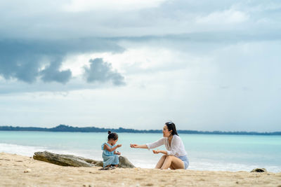 People sitting at beach against sky