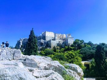 Trees and rocks against clear blue sky