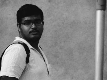 Portrait of young man standing against wall