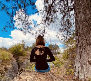 Rear view of woman standing against trees