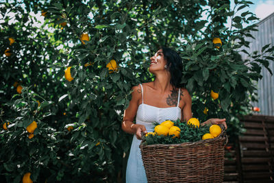 Young woman standing by tree in basket