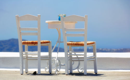 Empty chairs on beach against clear sky