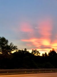 Silhouette trees on field against sky at sunset