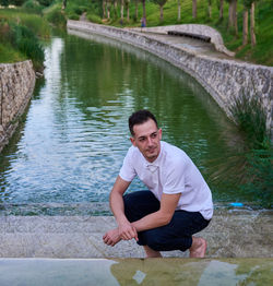 Portrait of young man sitting on river