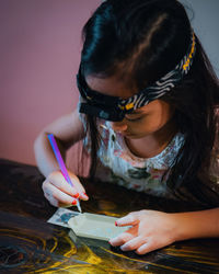 Side view of girl drawing on table