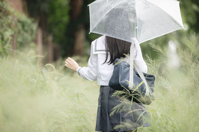 Midsection of man holding umbrella on field during rainy season