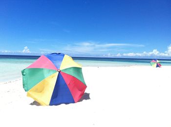 Multi colored umbrella on beach against sky