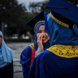 Smiling university students in graduation gowns