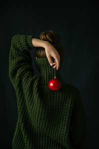 Christmas tree and red decor conceptual portrait of  girl in  green sweater and red christmas ball