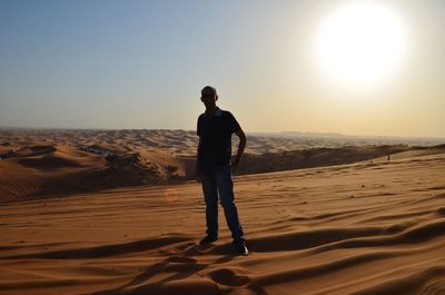 Man standing on sand dune at sunset