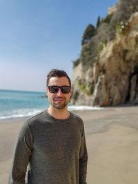Portrait of man wearing sunglasses standing at beach