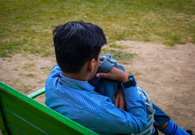 High angle view of boy sitting on bench