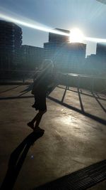 Man walking on street in city against bright sun