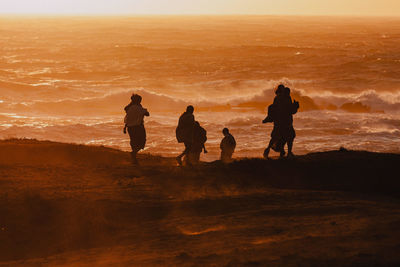 Silhouette people on beach during sunset