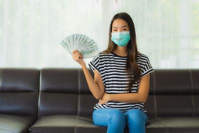 Full length of woman sitting on sofa at home