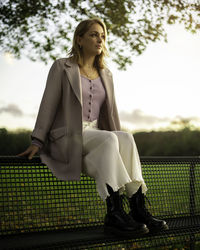 Full length of young woman sitting on tree