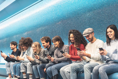 Friends using smart phones while sitting on seat