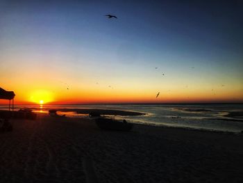 Scenic view of beach against clear sky during sunset