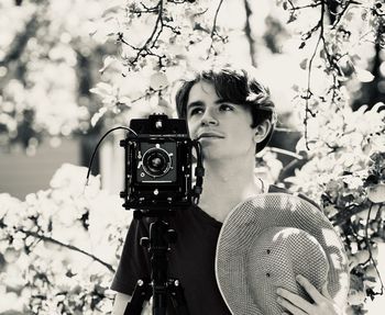 Young man and old analog photo camera in the garden