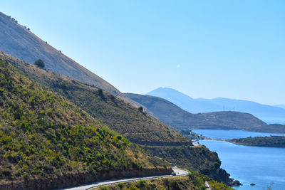 Scenic view of river amidst mountains against clear blue sky