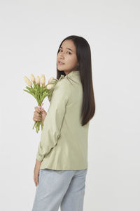 Side view of young woman standing against white background