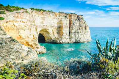 Rock formation by sea against sky