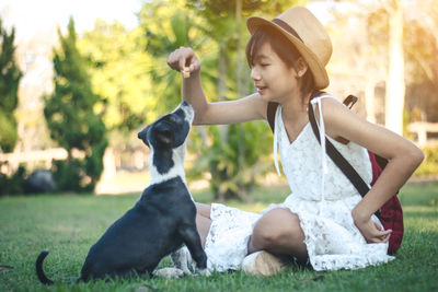 Rear view of woman with dog sitting on grass
