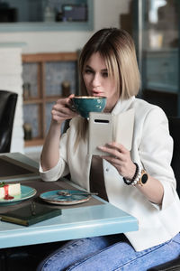 Young woman using mobile phone at table