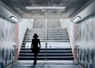 Rear view of silhouette man walking on staircase in building