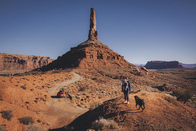 A woman with a child and a dog is standing on a hill, valley of gods