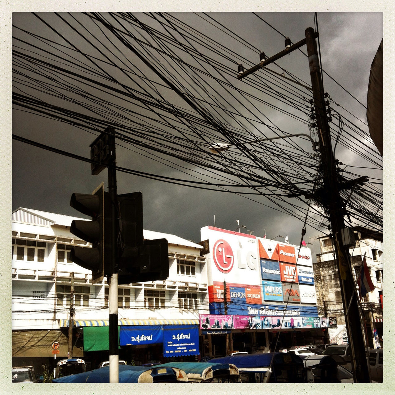 transportation, transfer print, building exterior, city, built structure, power line, architecture, mode of transport, communication, auto post production filter, car, street, land vehicle, text, sky, western script, city life, cable, electricity pylon, day