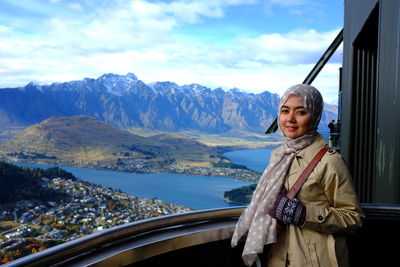 Portrait of woman standing in balcony against mountain range