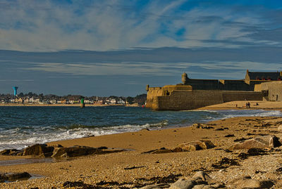 Buildings on beach against cloudy sky