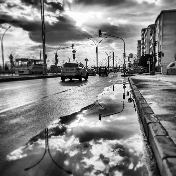 sky, cloud - sky, cloudy, building exterior, street light, cloud, architecture, built structure, transportation, street, mode of transport, weather, city, reflection, car, outdoors, water, overcast, incidental people, land vehicle