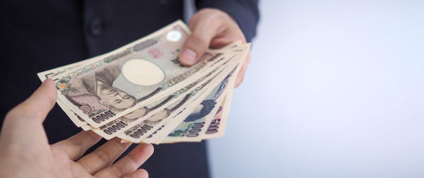 Midsection of person holding paper against white background