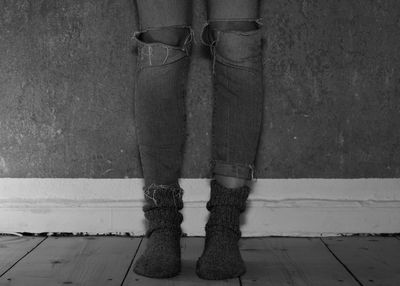 Low section of woman standing on floor against wall