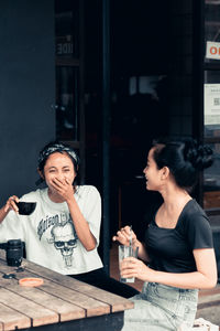 Side view of young woman sitting on table