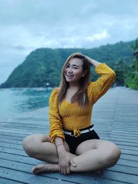 Beautiful young woman sitting against yellow water