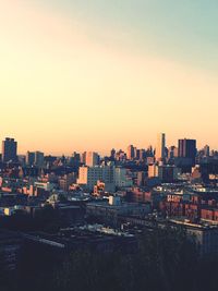 Buildings in city against clear sky during sunset