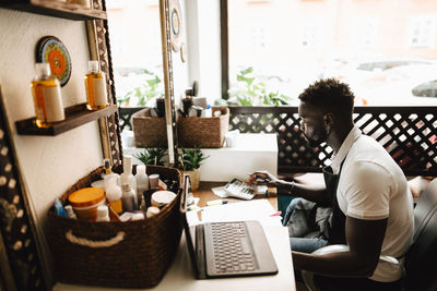 Male owner calculating financial bill at table in hair salon