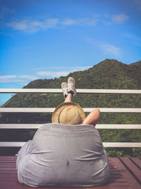 Rear view of man sitting against sky