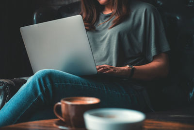 Midsection of businesswoman using laptop while sitting in office