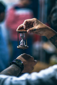 Close-up of man holding hourglass against blurred background