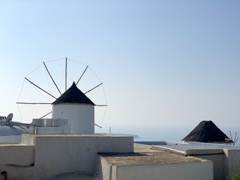 Traditional windmill by sea against clear sky