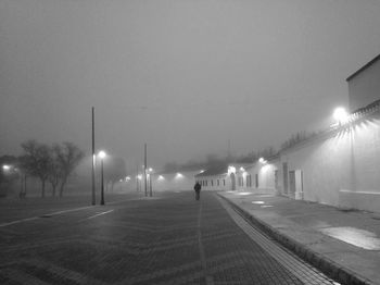 Illuminated street lights on road against sky at night