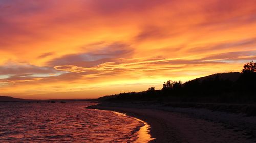 Scenic view of sea against dramatic sky during sunset