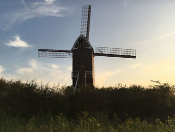 Traditional windmill on field against sky at sunset